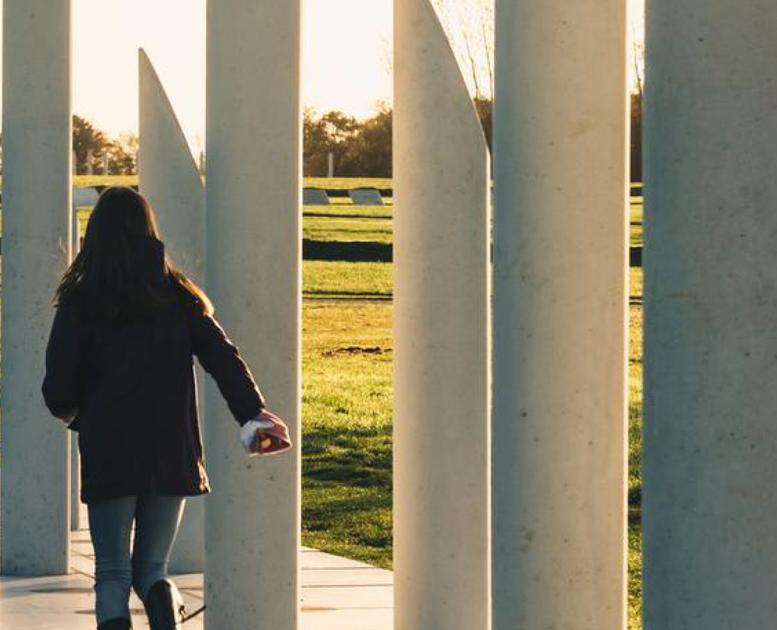 En person går langs de hvide betonpiller, der illustrerer hvor palisaden gik omkring Gorm den Gamles fæstningsværk